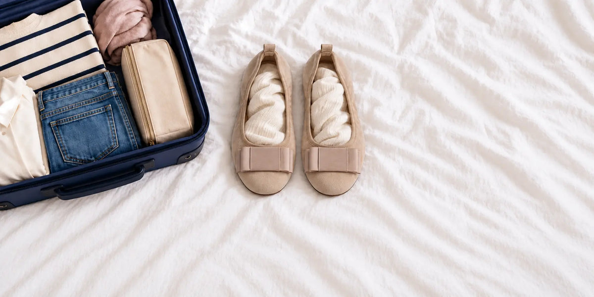 Beige CAMBIO Ballerinas mit weicher Füllung neben einem geöffneten Reisekoffer