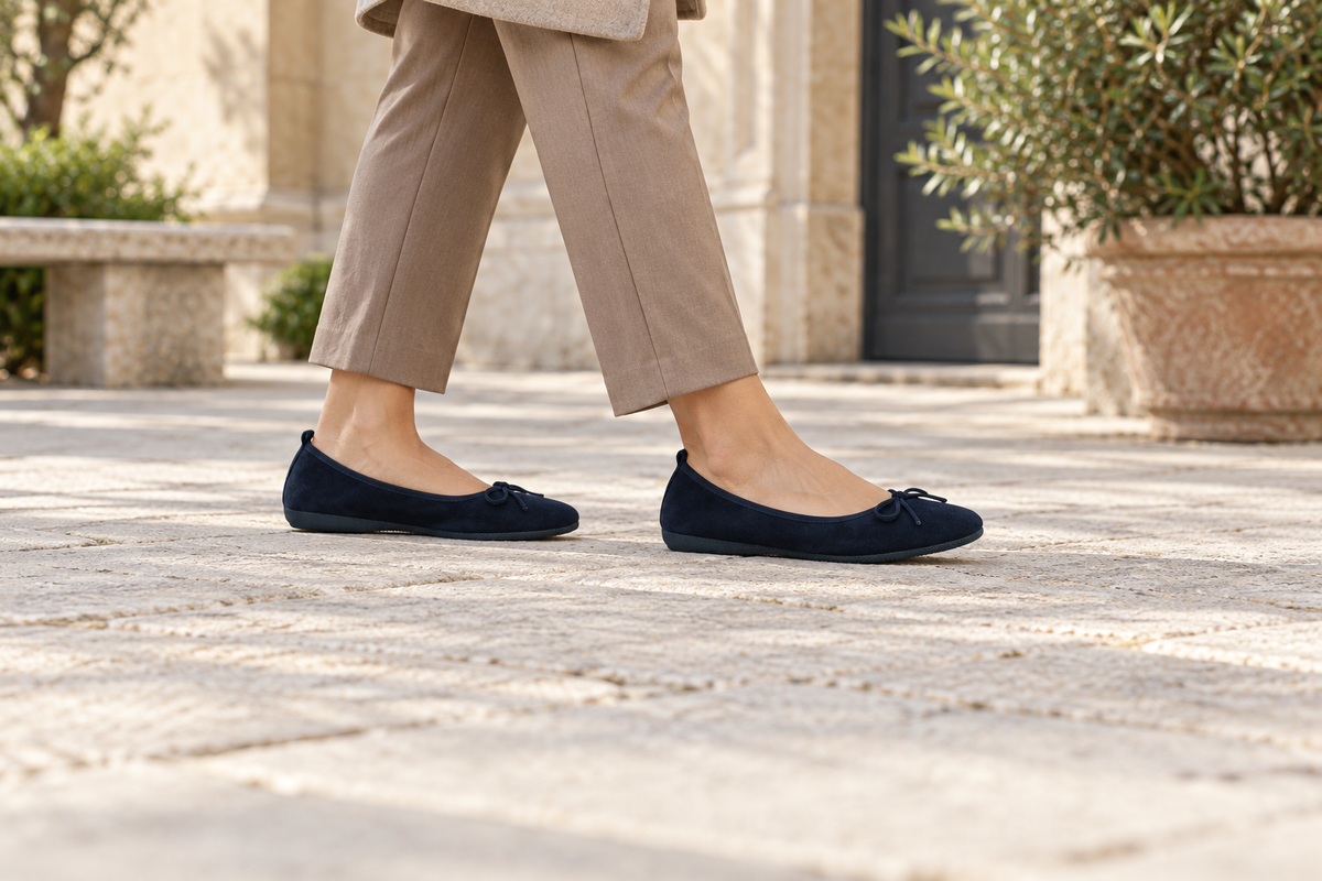 Dunkelblaue BASIC Ballerinas aus Veloursleder zu einer taupefarbenen Hose beim Gehen im Innenhof