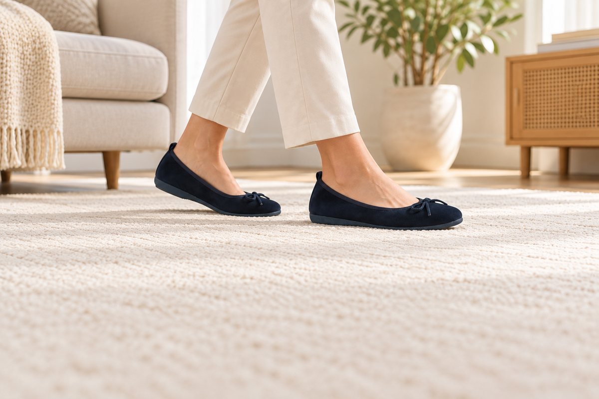 Dunkelblaue BASIC Ballerinas aus Veloursleder bei kurzen Schritten auf einem hellen Teppich